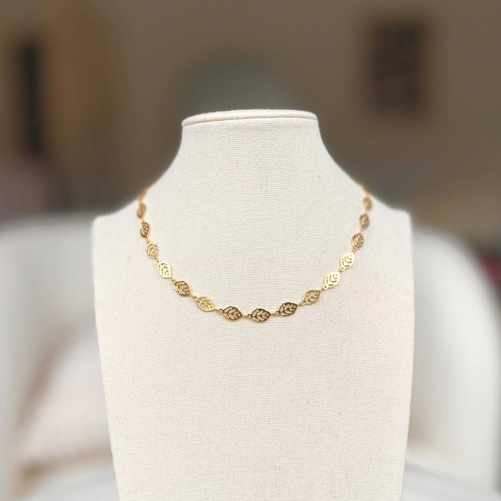 Gold leaf charm chain necklace on a linen bust