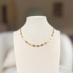 Gold leaf charm chain necklace on a linen bust