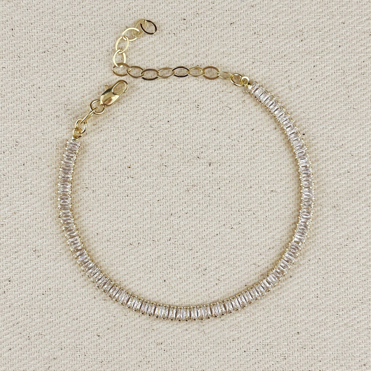Gold filled baguette tennis bracelet with extender chain on linen