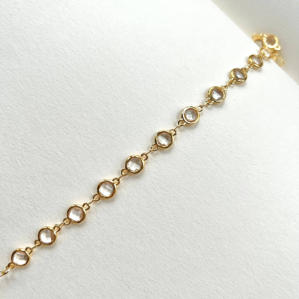 Gold filled crystal charm bracelet close up on white paper