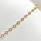 Gold filled crystal charm bracelet close up on white paper