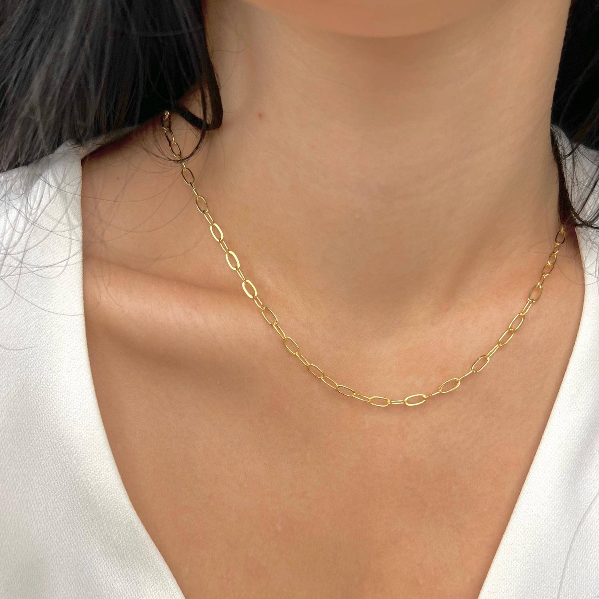 Paperclip chain necklace worn at the collarbone with a white top