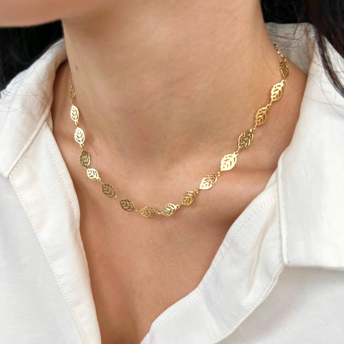 Gold filled leaf charm necklace worn as a choker with a white shirt