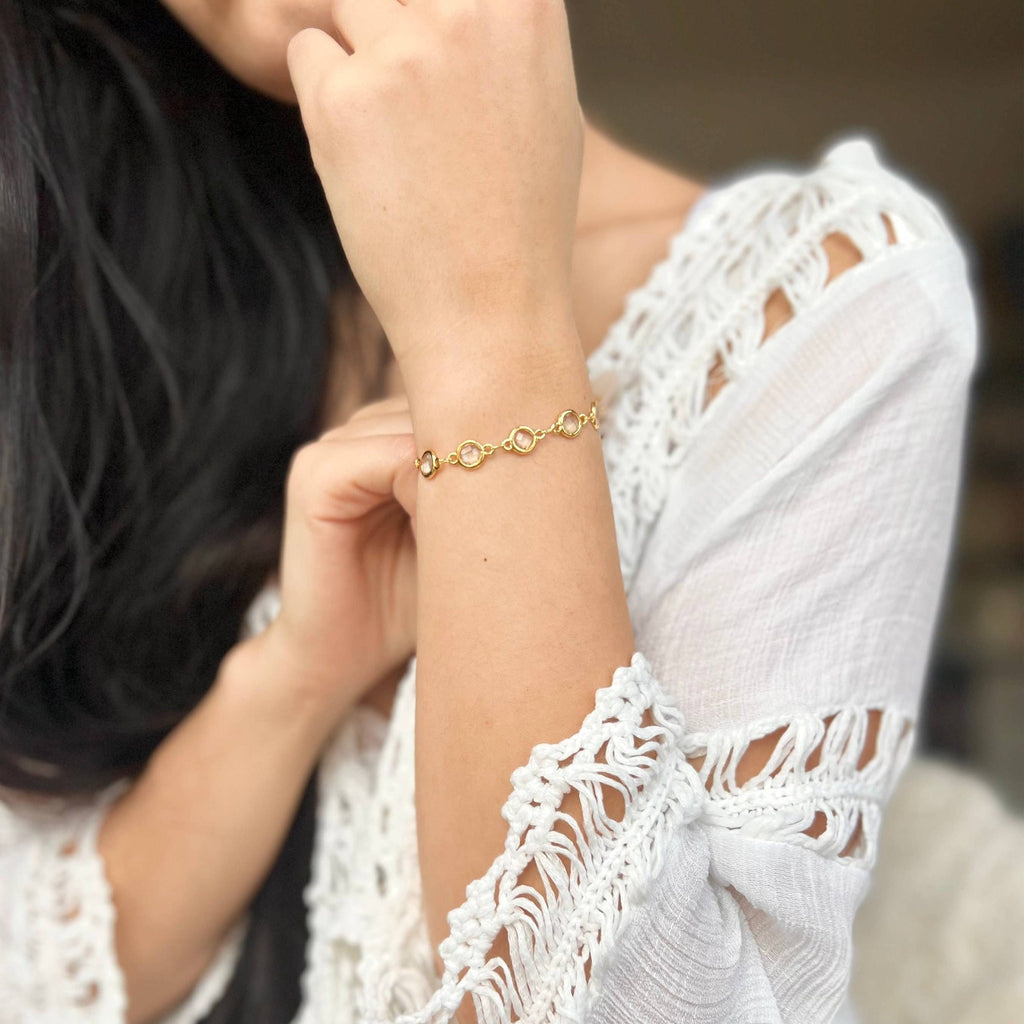 Crystal charm bracelet worn on the wrist with a white lace top