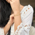 Crystal charm bracelet worn on the wrist with a white lace top
