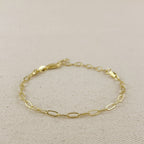 Gold paperclip bracelet with clasp on linen