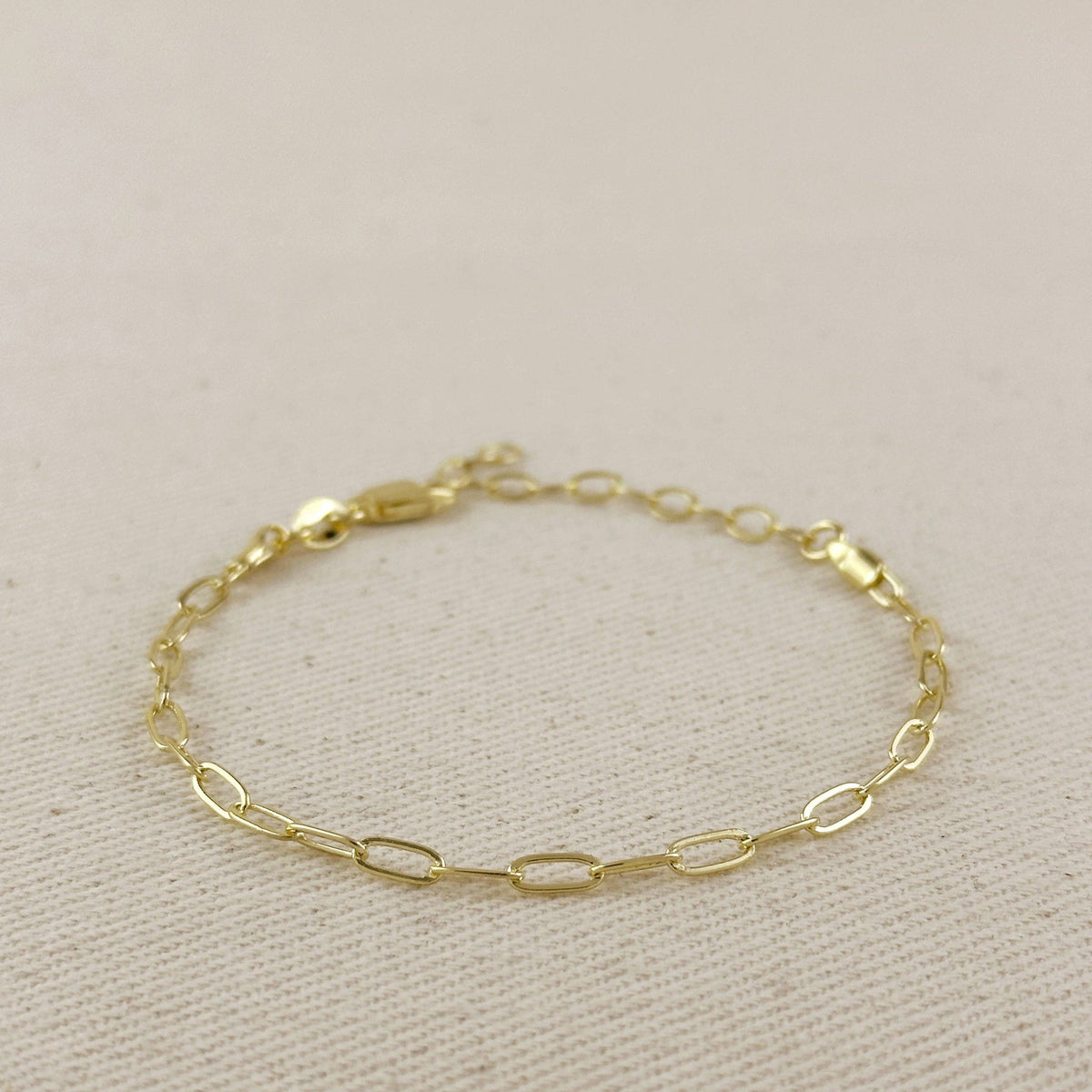 Gold paperclip bracelet with clasp on linen