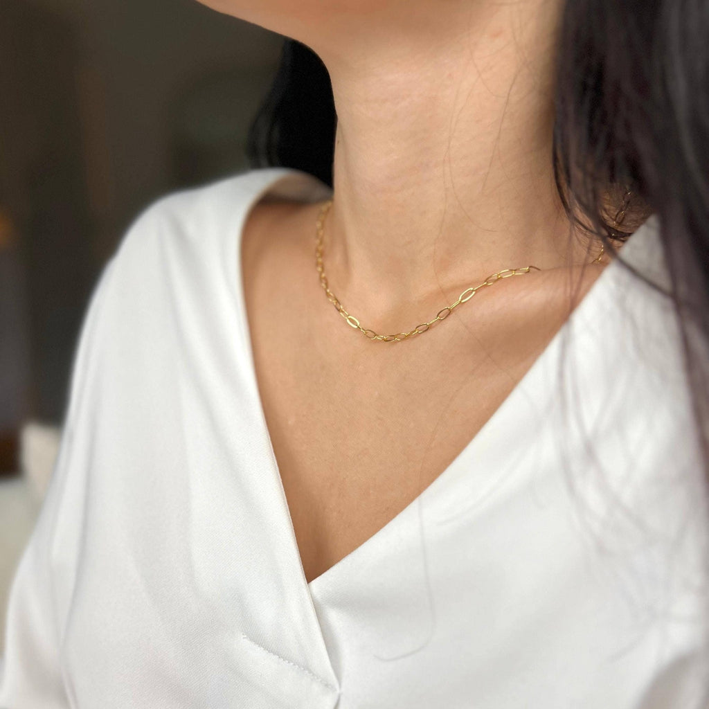 Gold paperclip chain necklace worn close to the neck