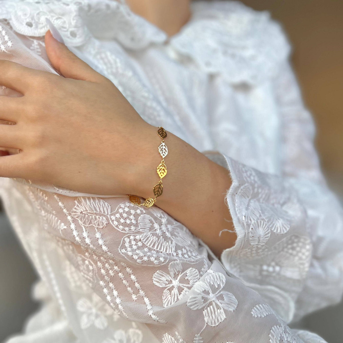 Leaf charm chain bracelet worn on the wrist with white lace