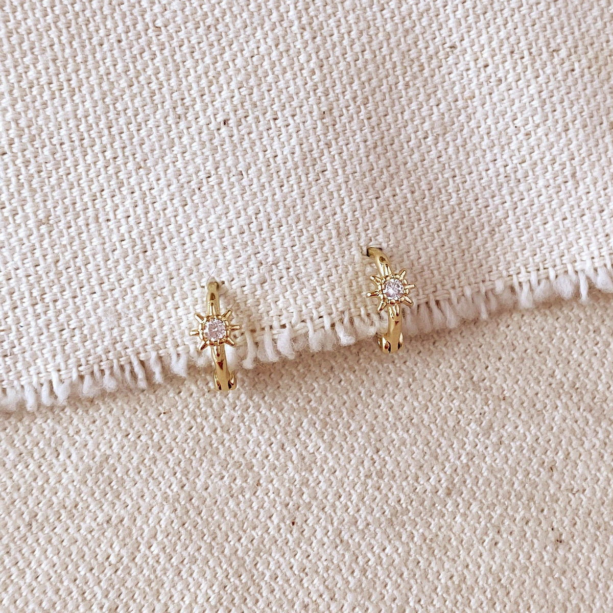 Gold starburst mini hoops on linen