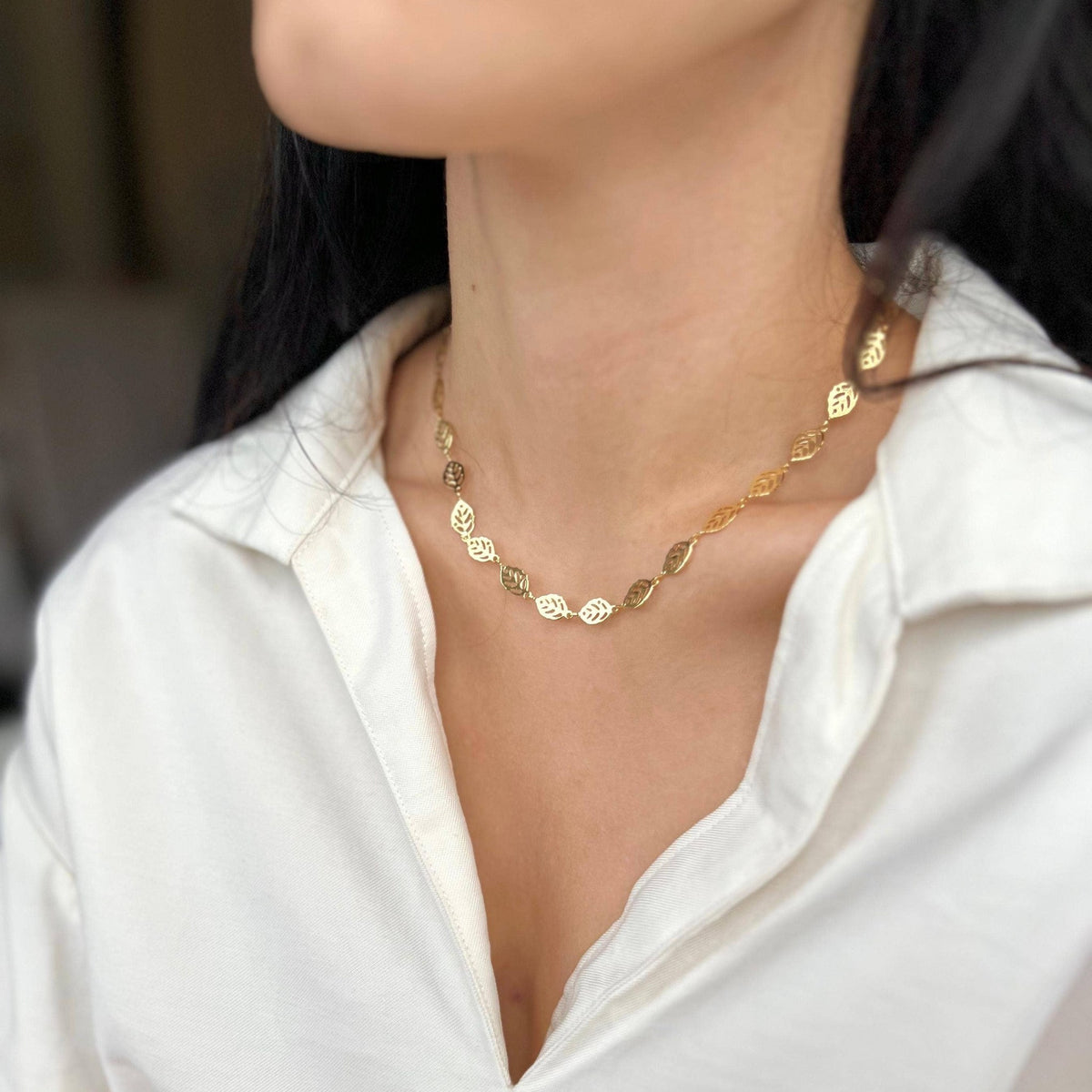 Leaf charm necklace worn at the collarbone