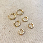 Set of gold pavé hoop earrings on linen
