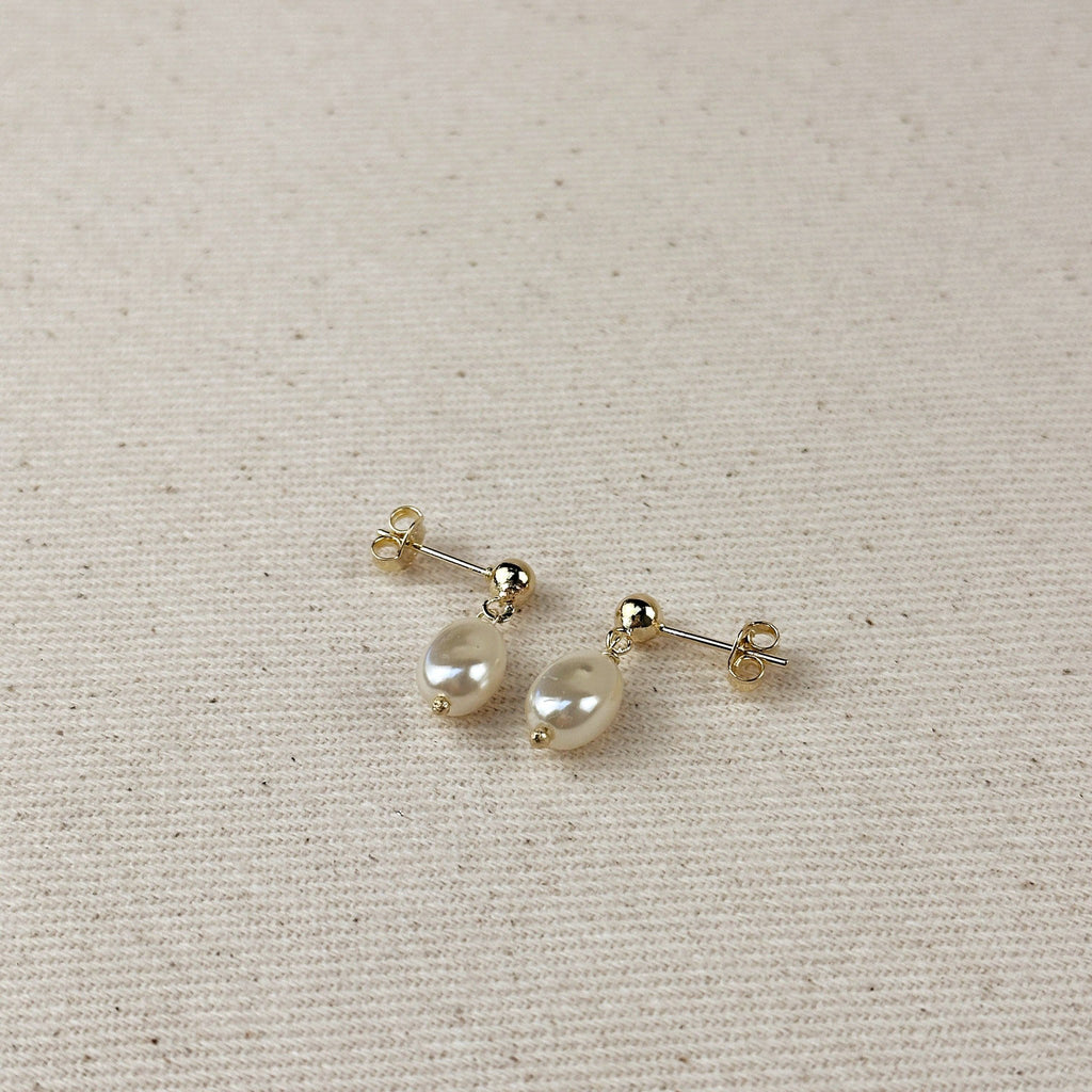 Pair of baroque pearl drop earrings on linen