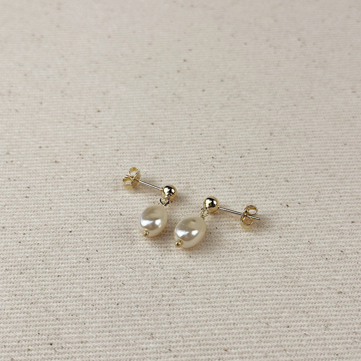 Pair of baroque pearl drop earrings on linen