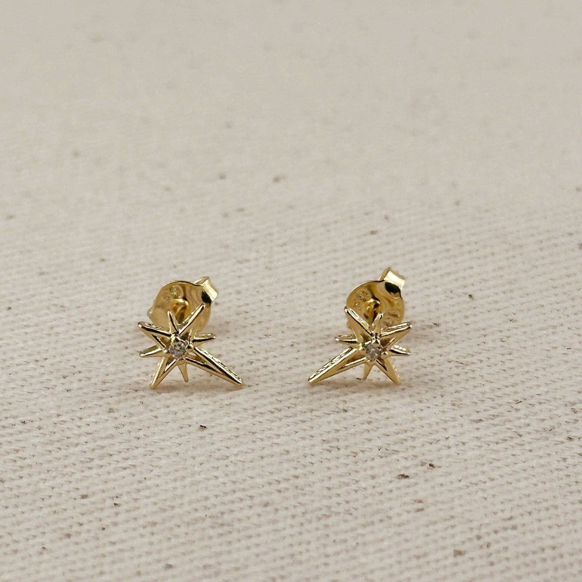 Gold starburst studs with butterfly backs on linen