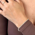 Marquise tennis bracelet worn on the wrist with a gold necklace