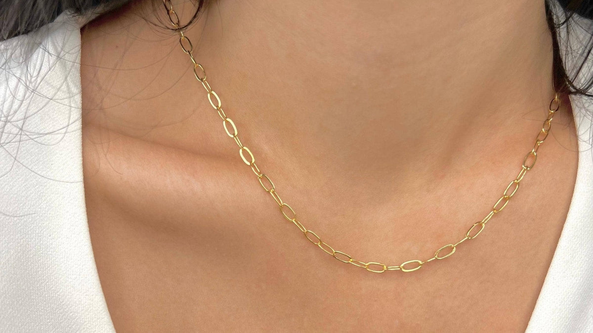 Gold paperclip chain necklace worn at the collarbone